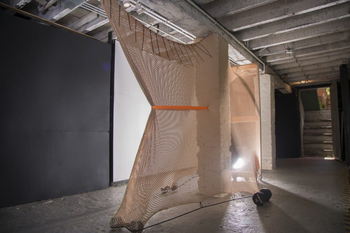 Leeza Meksin, Landing Gear, Site-specific Installation, Fishnet, wood & steel frame, dumbbells, douche bag, chain, paint, latex tubing, zip ties. 108” x 72” x 24”, 2014.  